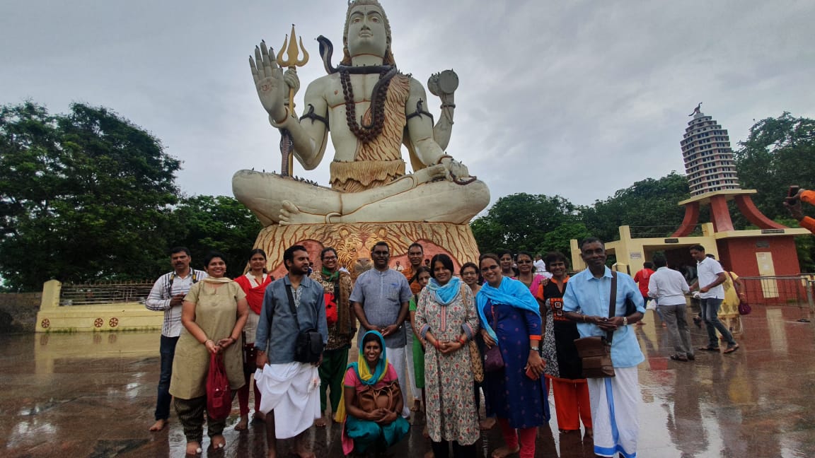 Travellers at a large seated Lord Shiva statue on a rainy day