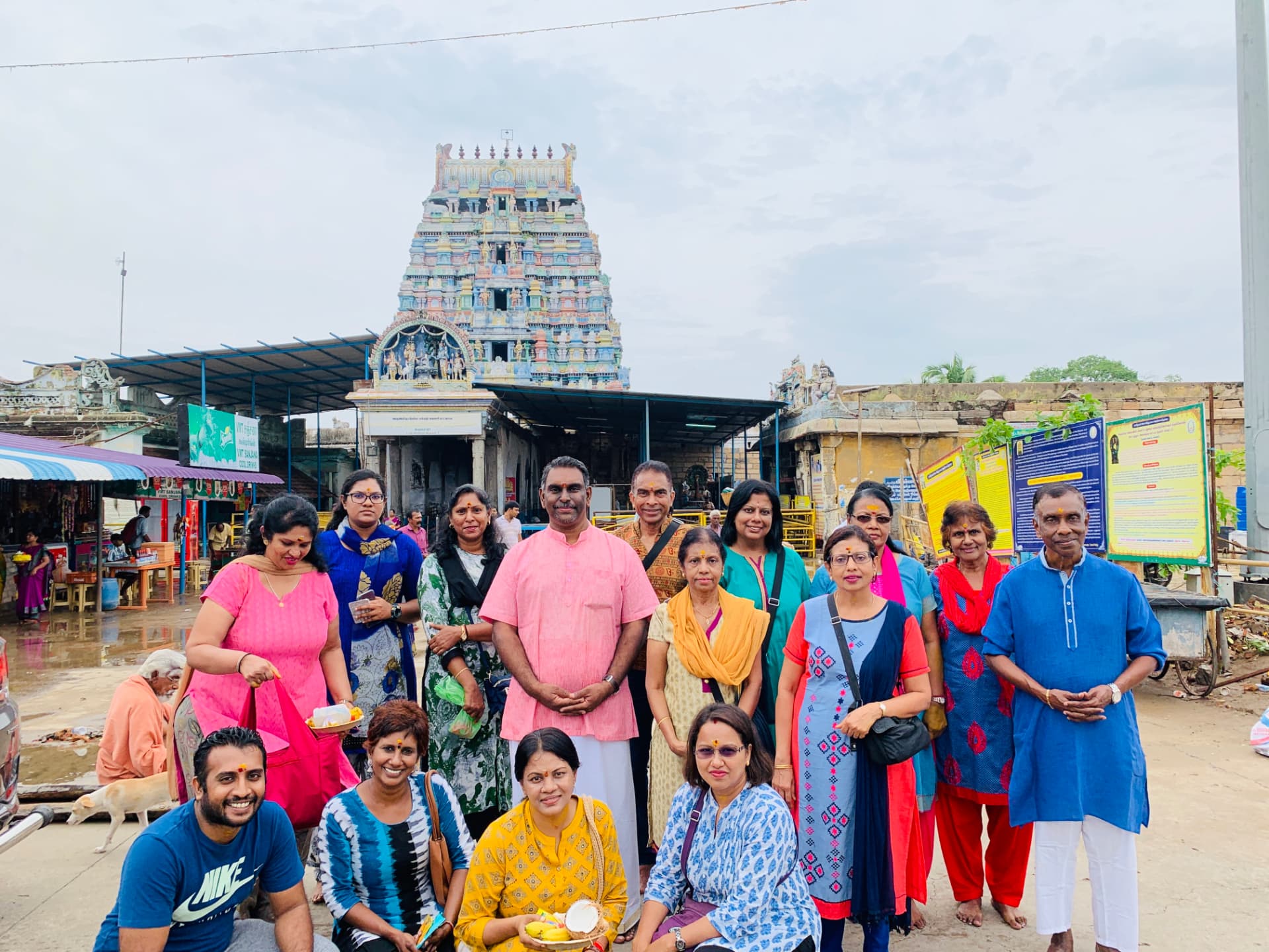Pilgrim group with pooja offerings outside a colourful South Indian temple