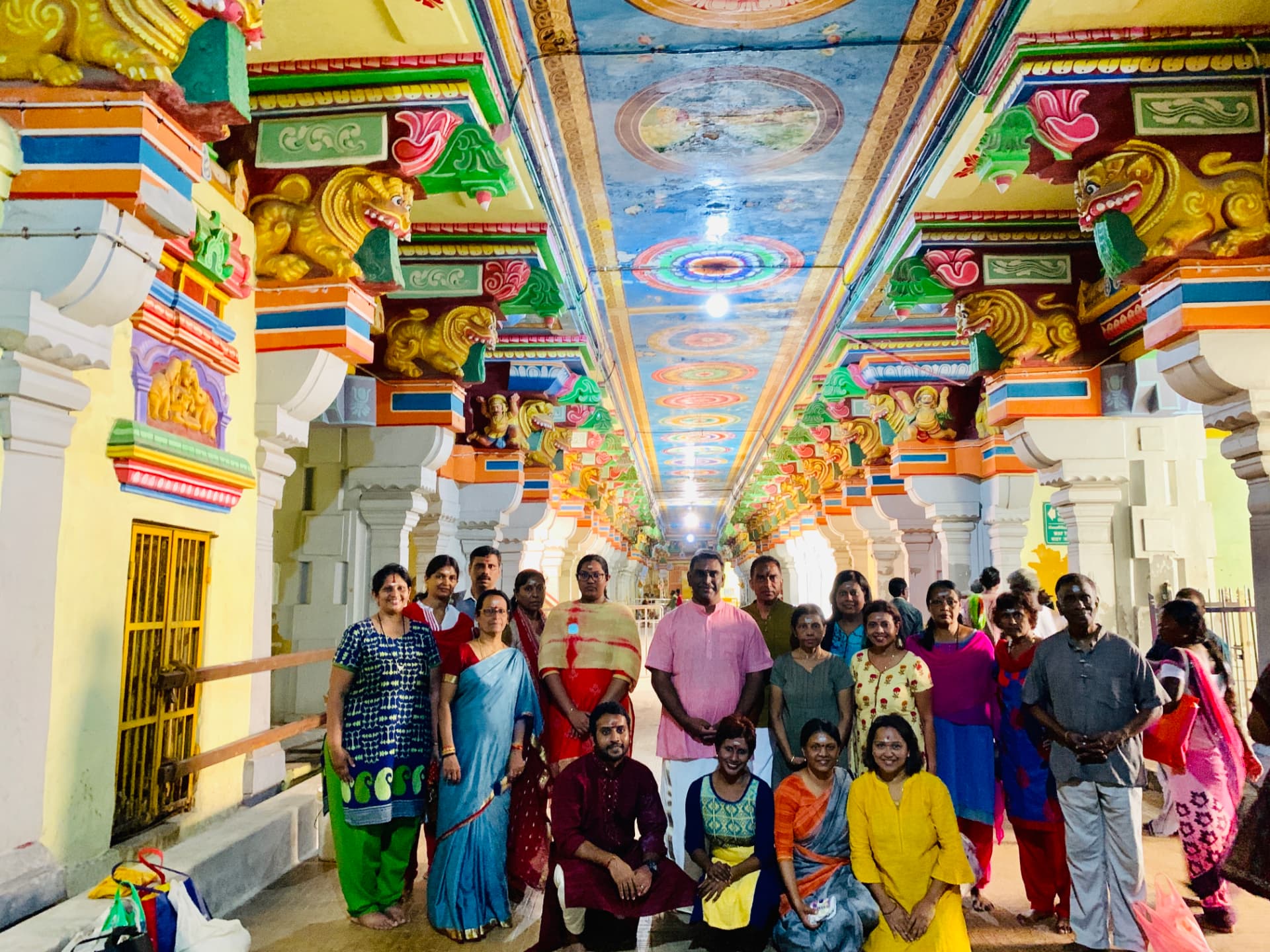 Tour group inside a painted temple corridor with carved pillars
